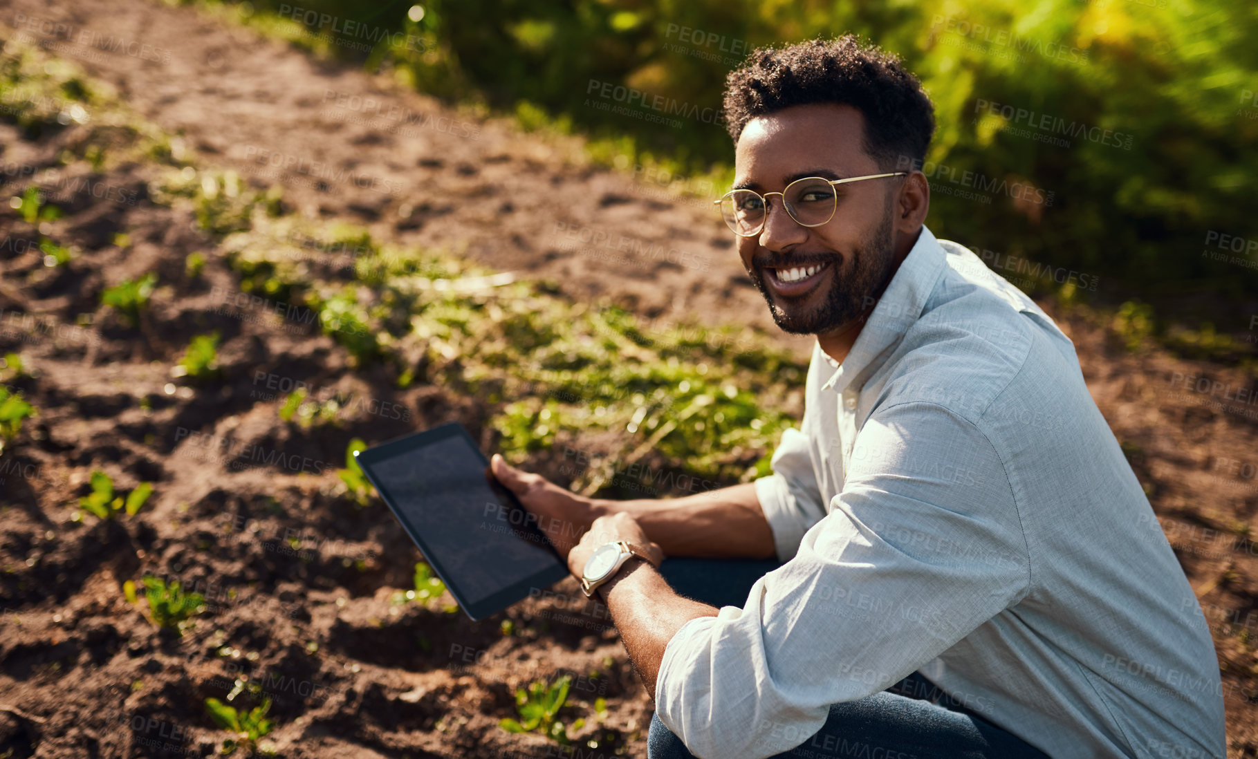 Buy stock photo Cropped portrait of a handsome young male farmer using a tablet while working on his farm