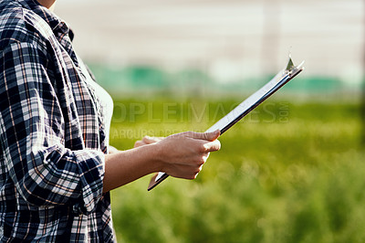 Buy stock photo Cropped shot of an unrecognizable female farmer looking over paperwork while working on her farm