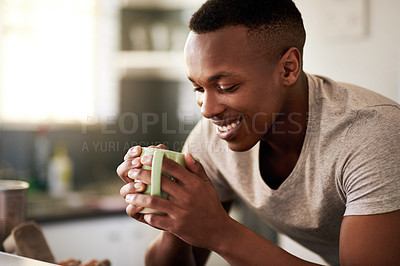 Buy stock photo Cropped shot of a handsome young man smiling while having a cup of coffee in his kitchen at home