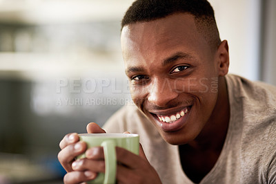 Buy stock photo Cropped portrait of a handsome young man smiling while having a cup of coffee in his kitchen at home