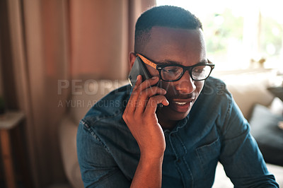 Buy stock photo Young student talking on a phone call to a friend, colleague or family member. Black male university or college learner studying design, marketing or architecture sitting and chatting at home