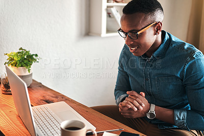 Buy stock photo Male online worker on his computer working freelance sitting in a home office alone. Casual digital employee reading and looking at tech and web research. Young modern man doing a remote tech job