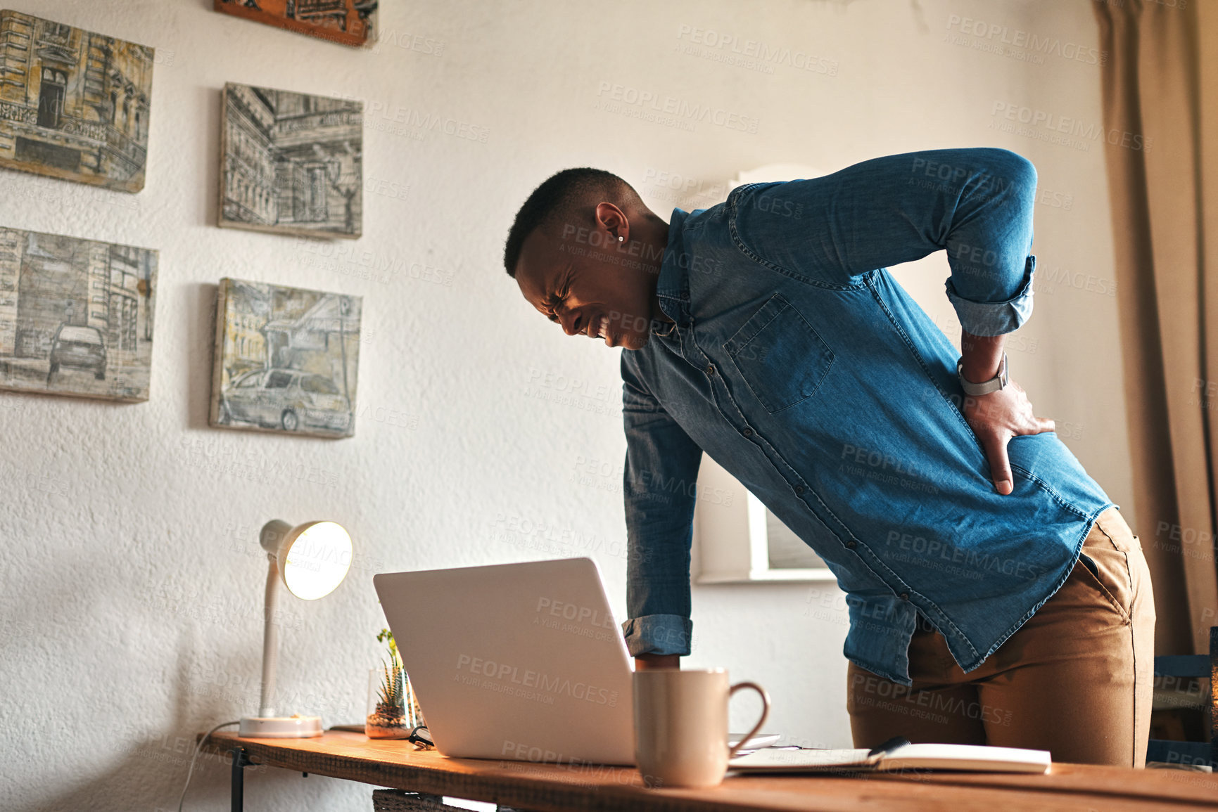 Buy stock photo Back pain, ache and sore body with a business man suffering from bad posture. Feeling hurt with cramp or stiff spine from being overworked. Young male entrepreneur working on a laptop in his office