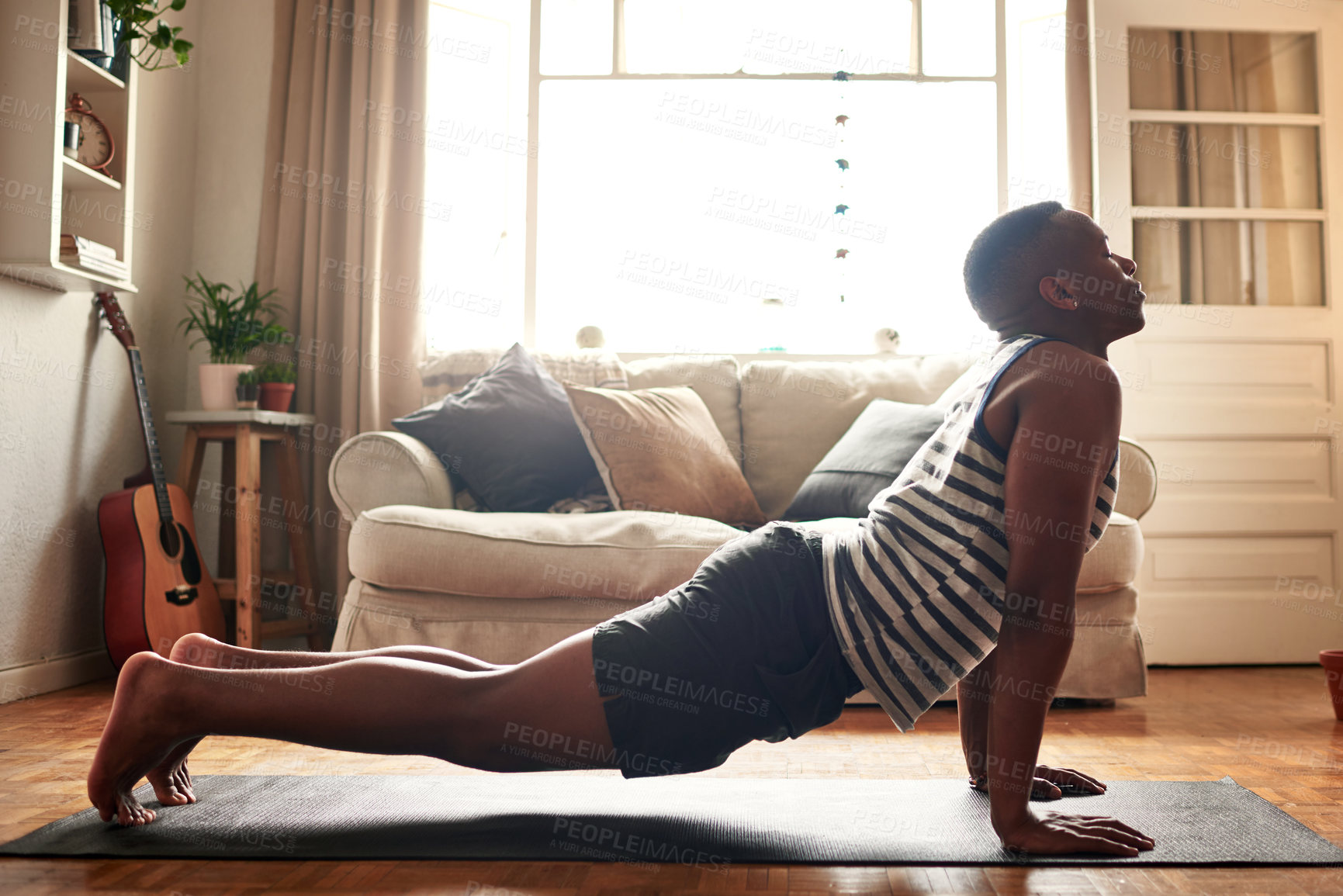 Buy stock photo Shot of a young man practising yoga at home during the day