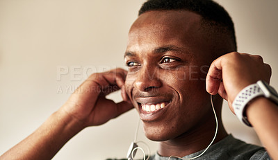 Buy stock photo Cropped shot of a handsome young man putting his earphones in his ears