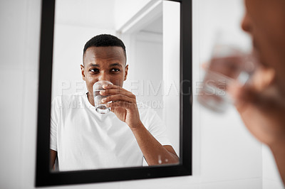 Buy stock photo Shot of a young man rinsing his mouth with water in the bathroom at home