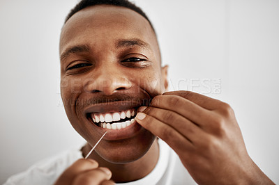 Buy stock photo Cropped shot of a young man flossing his teeth in the bathroom at home