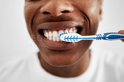 Buy stock photo Shot of a young man brushing his teeth in the bathroom at home