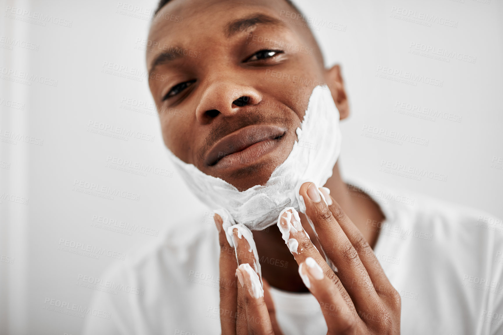 Buy stock photo Cropped shot of a young man applying shaving foam to his face
