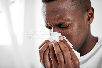 Buy stock photo Cropped shot of a young man blowing his nose at home
