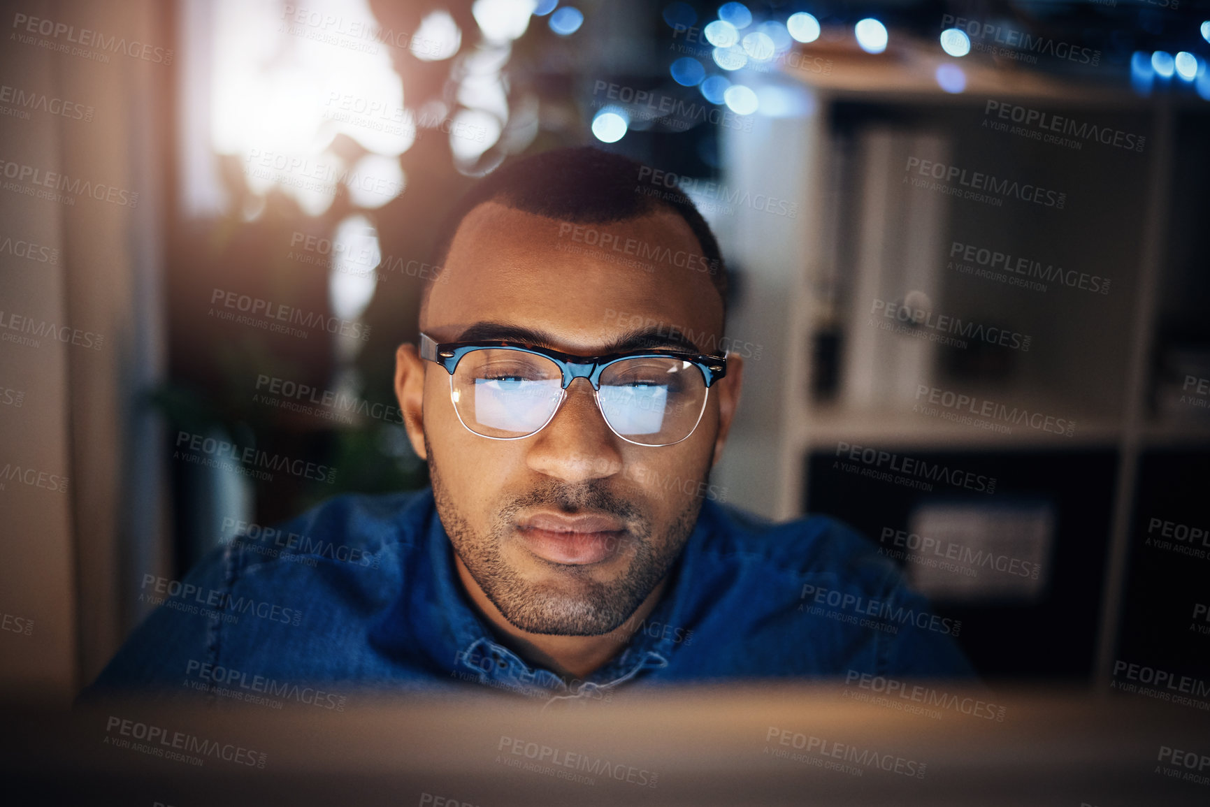 Buy stock photo Shot of a young businessman working on a computer in an office at night