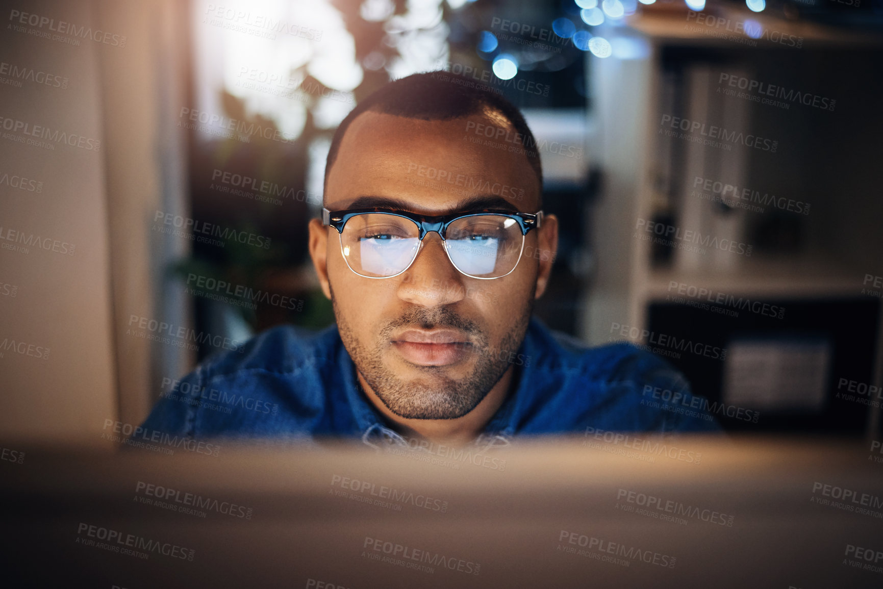 Buy stock photo Shot of a young businessman working on a computer in an office at night