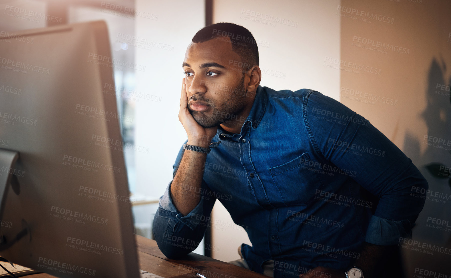 Buy stock photo Shot of a young businessman looking bored while working in an office at night