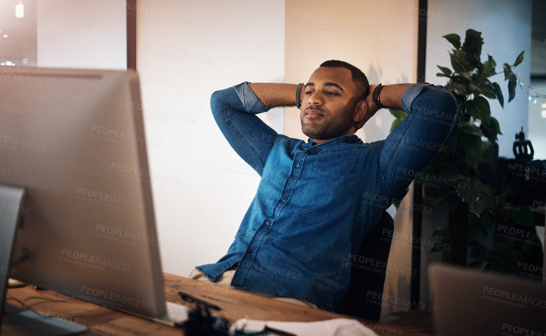 Buy stock photo Shot of a young businessman taking a break at his while working in an office at night
