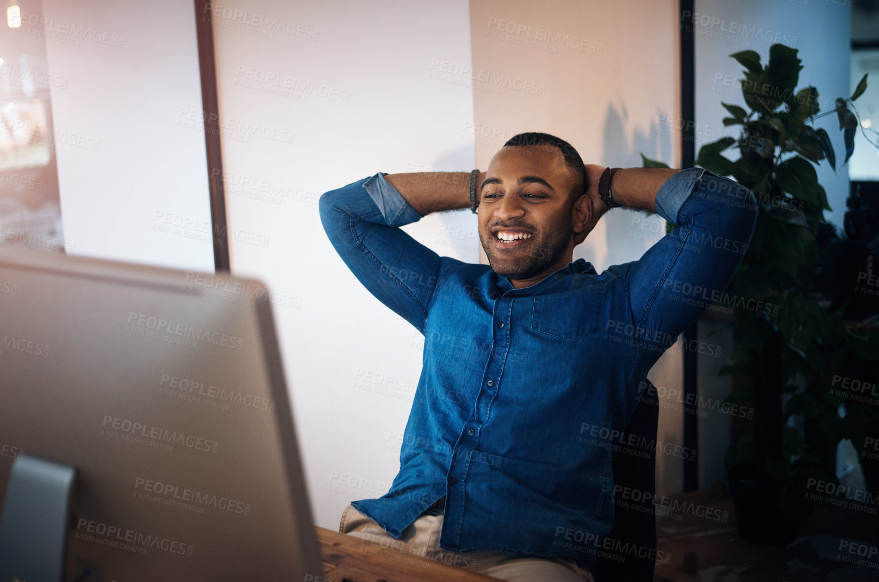 Buy stock photo Shot of a young businessman taking a break at his desk while working in an office at night