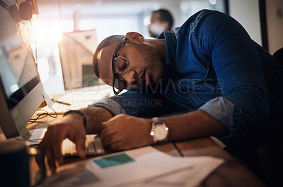 Buy stock photo Shot of a young businessman sleeping at his desk in an office at night