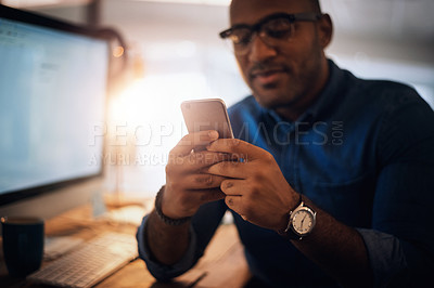 Buy stock photo Shot of a young businessman using a cellphone in an office at night