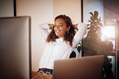 Buy stock photo Shot of a young businesswoman taking a break at her desk while working in an office at night