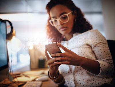 Buy stock photo Closeup shot of a young businesswoman using a cellphone while working in an office at night