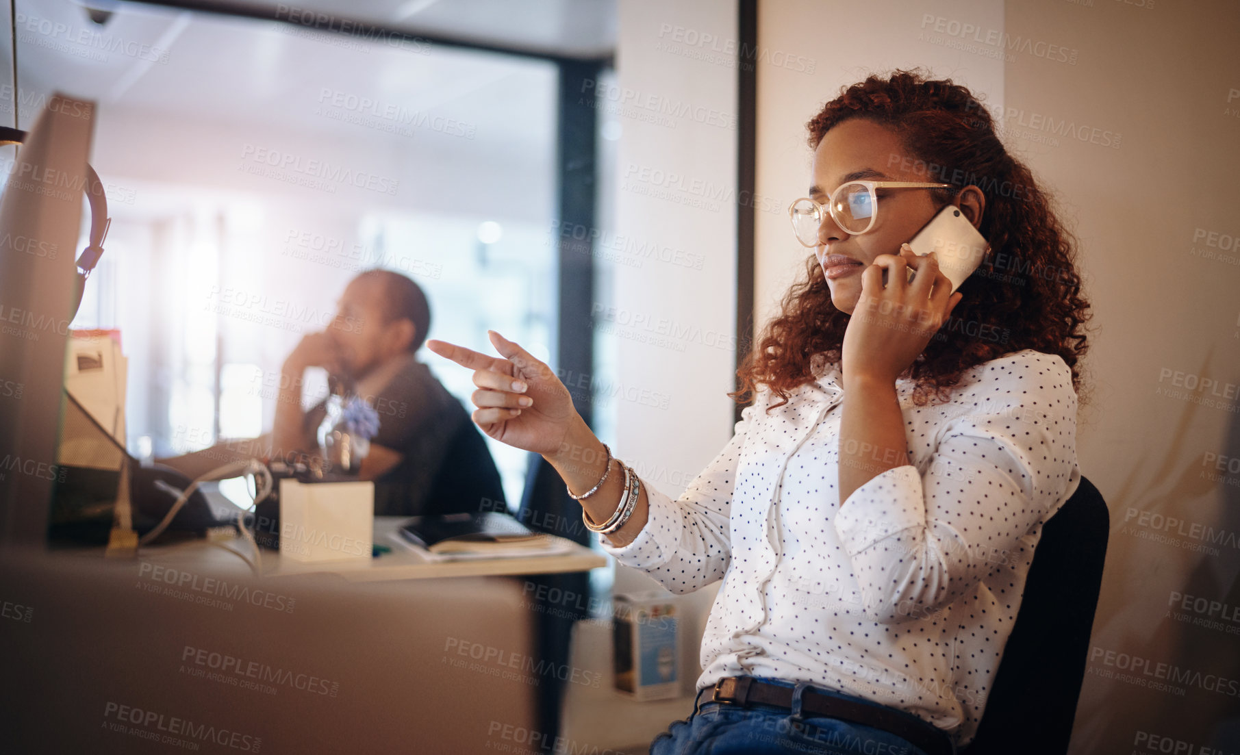 Buy stock photo Shot of a young businesswoman talking on a cellphone while working in an office at night