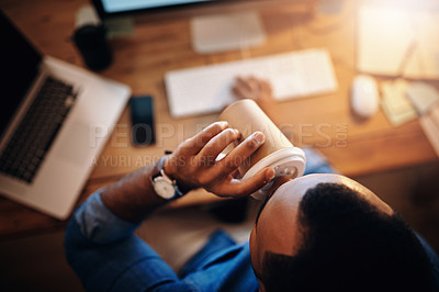 Buy stock photo High angle shot of a businessman drinking coffee while working in an office at night