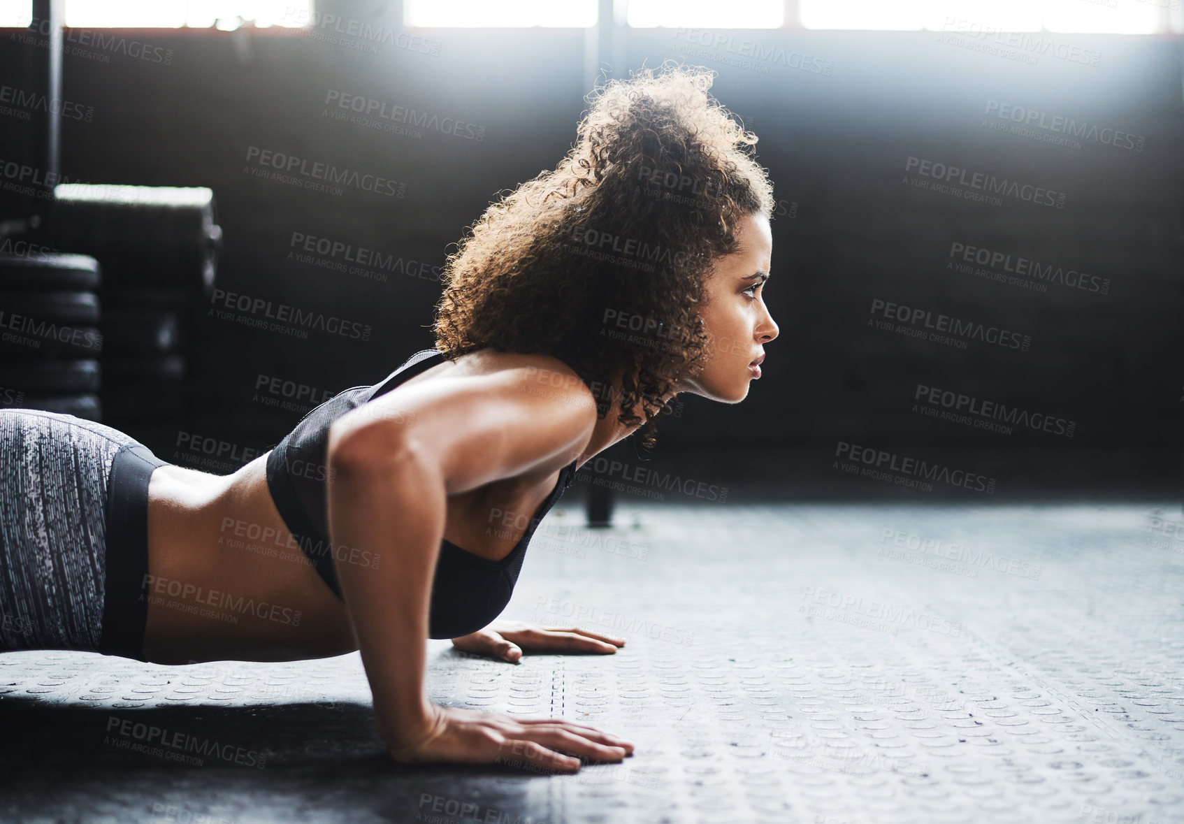 Buy stock photo Shot of a young woman doing pushups in a gym