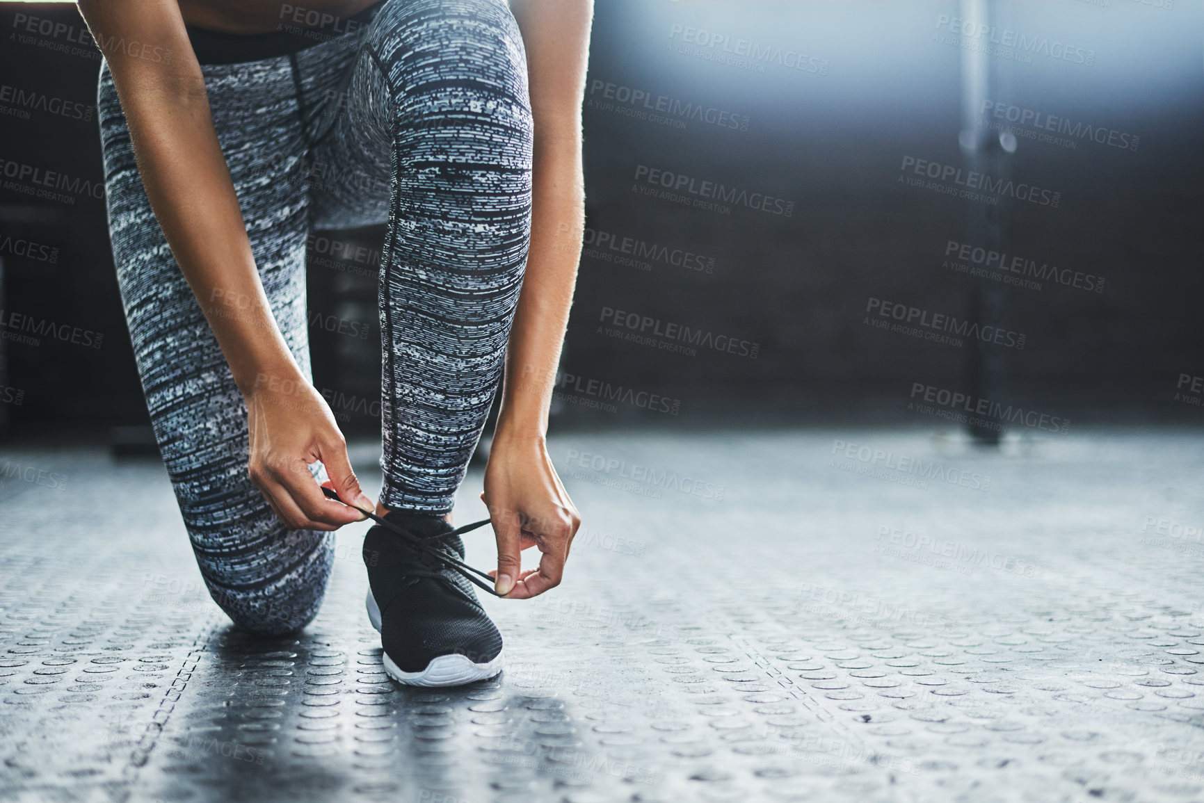 Buy stock photo Cropped shot of a woman tying her shoelaces in a gym