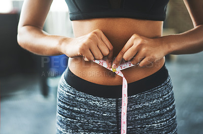 Buy stock photo Cropped shot of a fit young woman measuring her waist in a gym