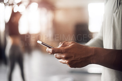Buy stock photo Shot of an unrecognizable man using a mobile phone in a gym