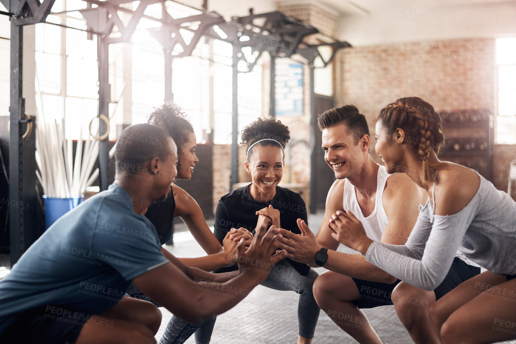 Buy stock photo Shot of a group of young people doing squats together during their workout in a gym
