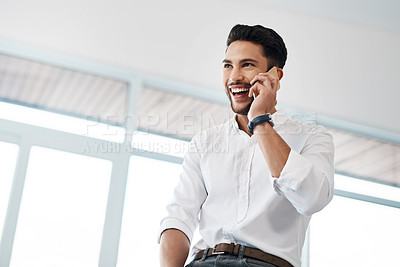 Buy stock photo Cropped shot of a handsome young businessman sitting in his office and talking on his cellphone