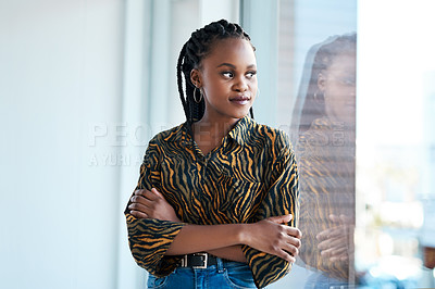 Buy stock photo Cropped shot of an attractive young businesswoman looking contemplative while standing with her arms folded in her office alone
