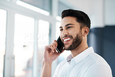 Buy stock photo Cropped shot of a handsome young businessman standing in his office and talking on his cellphone