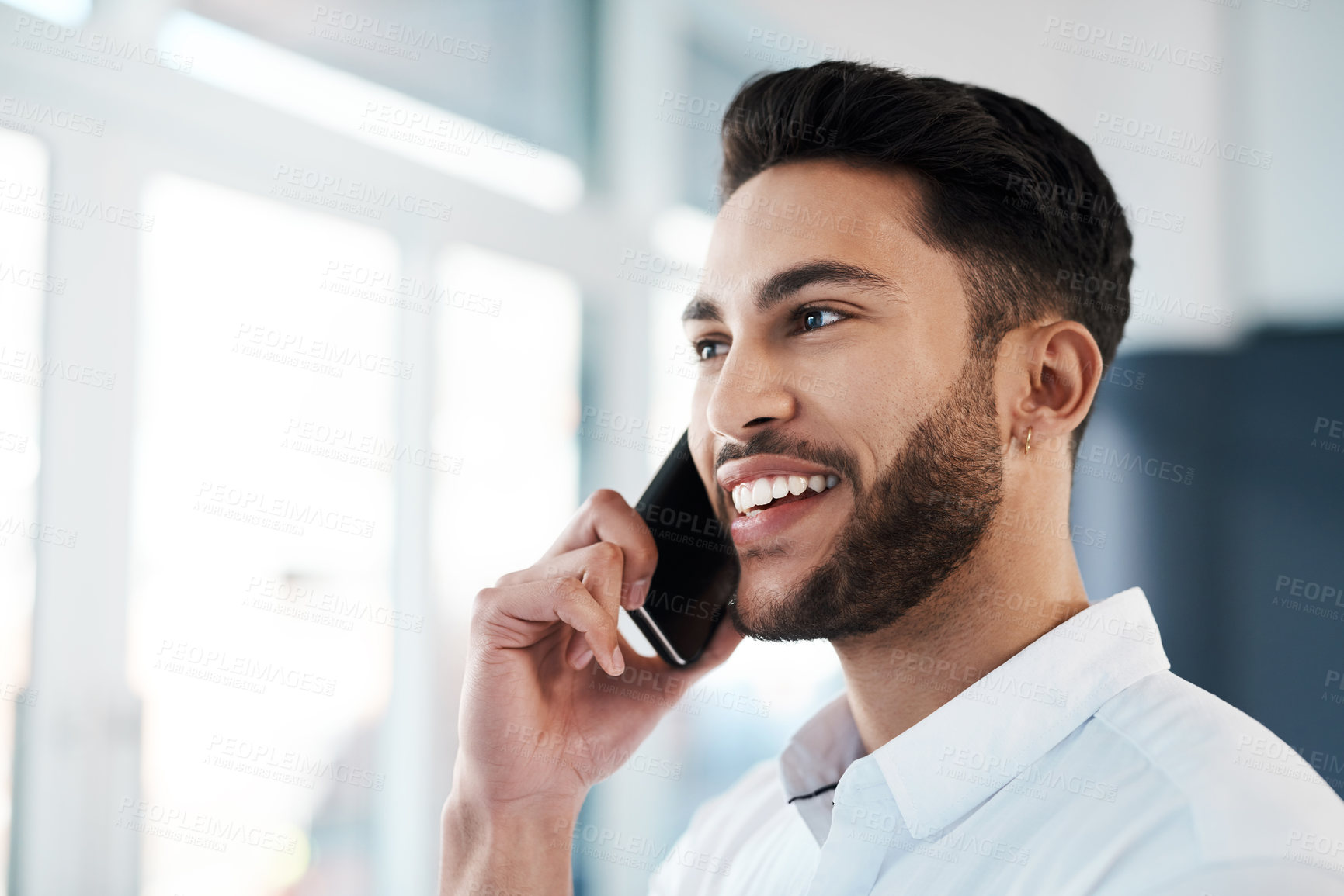 Buy stock photo Cropped shot of a handsome young businessman standing in his office and talking on his cellphone