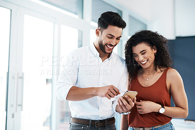 Buy stock photo Cropped shot of two young business colleagues standing together in the office and using a cellphone