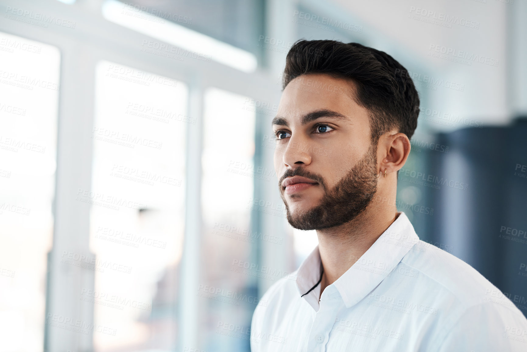 Buy stock photo Cropped shot of a handsome young businessman looking contemplative while standing in his office alone
