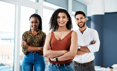 Buy stock photo Cropped portrait of an attractive young businesswoman standing with her arms crossed in front of her colleagues in the office