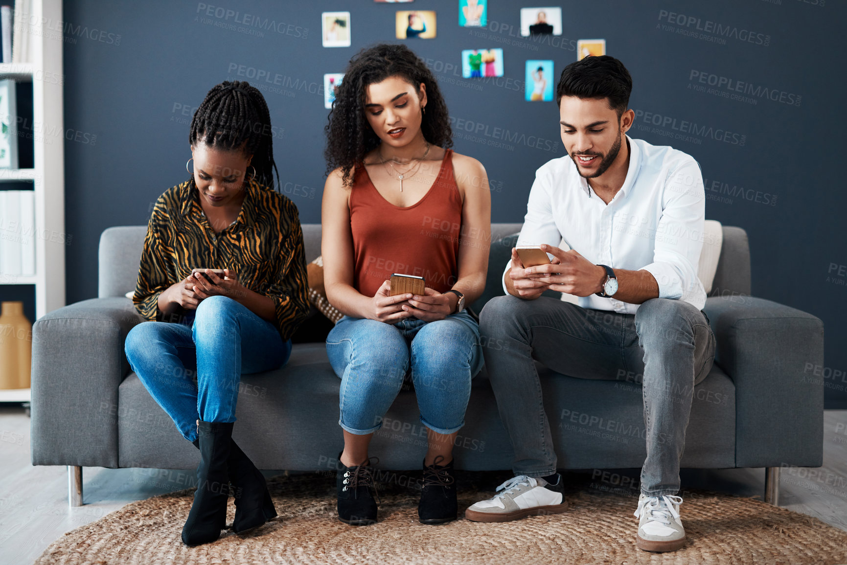Buy stock photo Full length shot of a diverse group of business colleagues sitting on a sofa together and using their cellphones