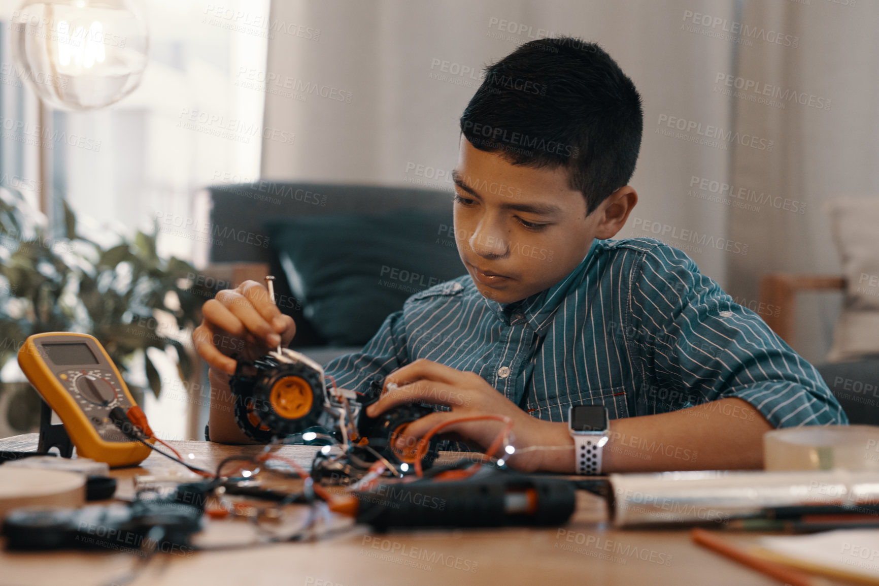 Buy stock photo Shot of a handsome young boy building a robotic toy car at home