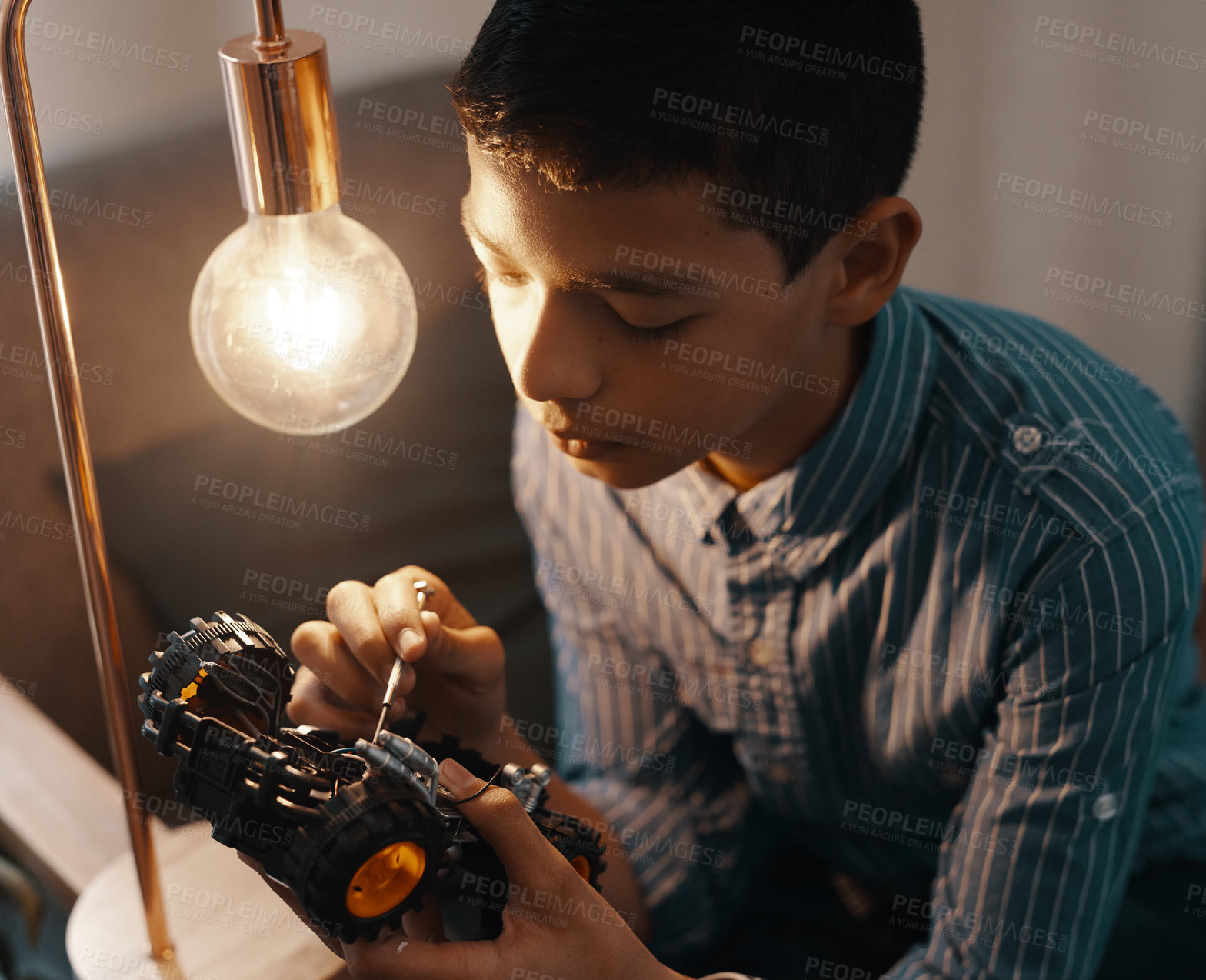 Buy stock photo Shot of a handsome young boy building a robotic toy car at home