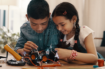 Buy stock photo Shot of two adorable young siblings building a robotic toy car together at home