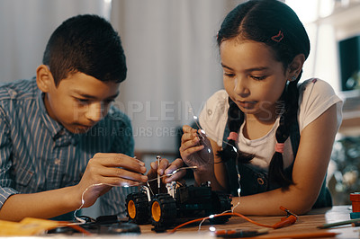 Buy stock photo Shot of two adorable young siblings building a robotic toy car together at home