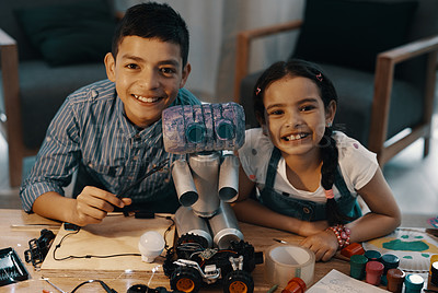 Buy stock photo Portrait of two adorable young siblings posing with their newly built toy robot at home