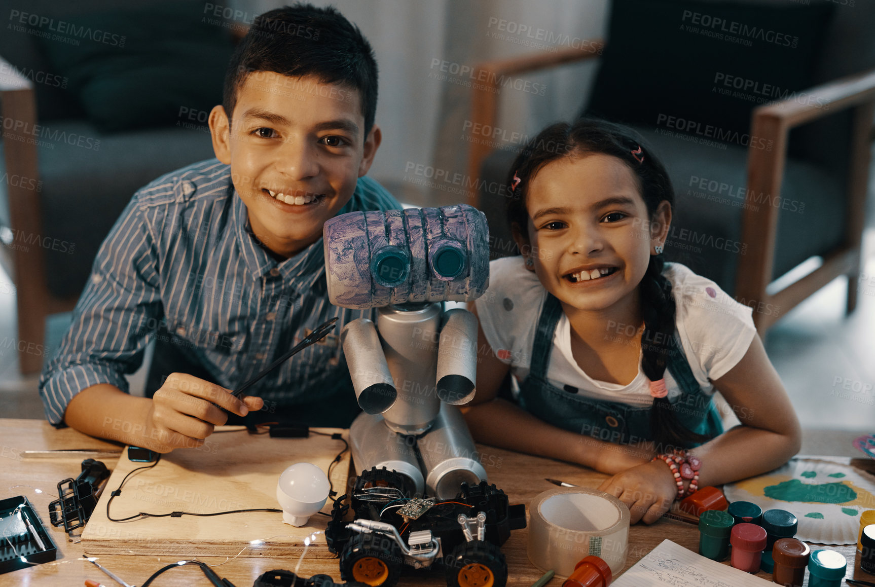 Buy stock photo Portrait of two adorable young siblings posing with their newly built toy robot at home