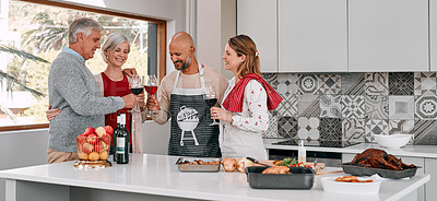 Buy stock photo Shot of a group of mature friends toasting with wine while preparing a Thanksgiving meal