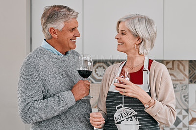 Buy stock photo Shot of a happy mature couple having red wine together while cooking at home