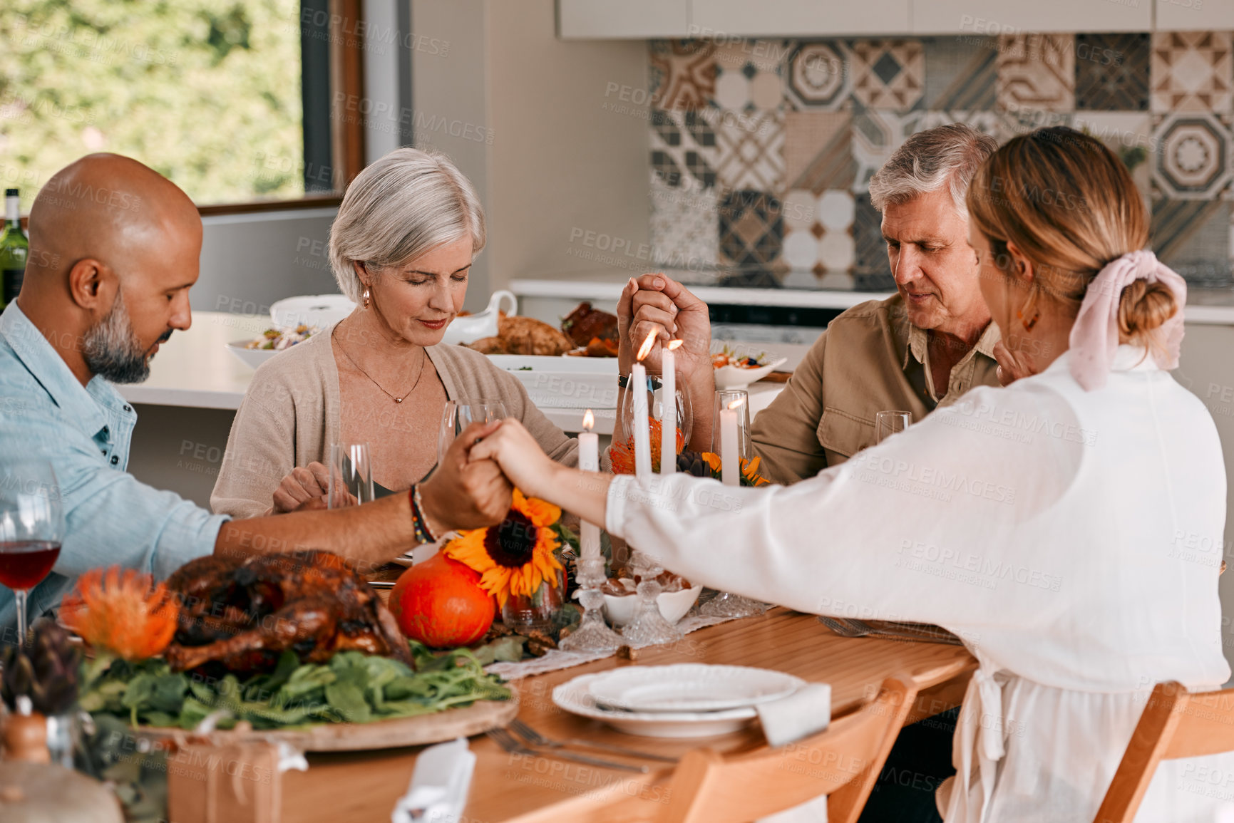 Buy stock photo Shot of a group of mature friends joining hands in prayer before having a Thanksgiving meal