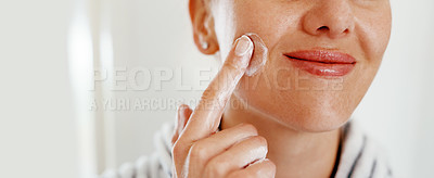 Buy stock photo Cropped shot of an unrecognizable woman looking cheerful while applying moisturizer on her at home