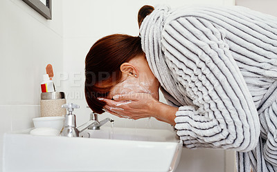 Buy stock photo Cropped shot of an unrecognizable woman washing her face in the bathroom sink at home