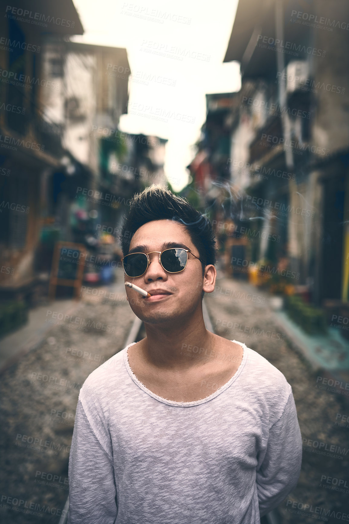 Buy stock photo Man, portrait and smoking in city with sunglasses, attitude and fashion for travel. Person, designer shades and cigarette on Vietnam street with confidence, edgy style and nicotine addiction in smoke